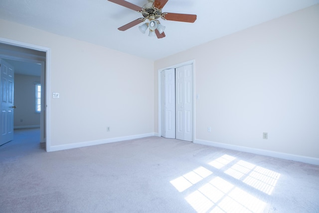 carpeted empty room featuring ceiling fan and baseboards