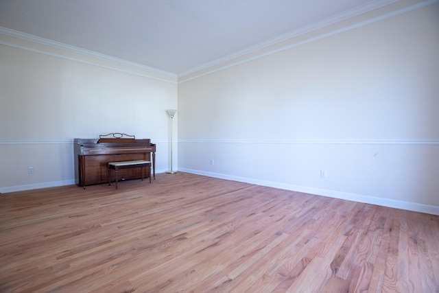 spare room with ornamental molding, baseboards, and wood finished floors