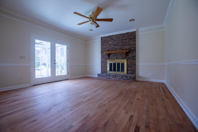 unfurnished living room featuring a brick fireplace, crown molding, baseboards, and wood finished floors