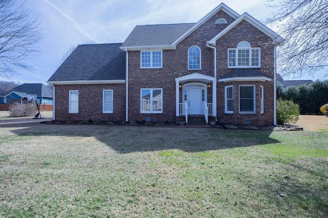 traditional home with brick siding, roof with shingles, and a front yard