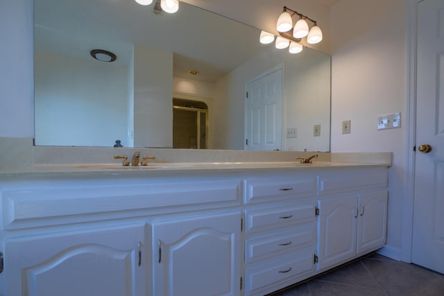 bathroom with double vanity, a sink, a shower with shower door, and tile patterned floors