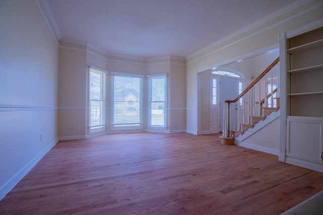 foyer entrance with baseboards, stairs, ornamental molding, and wood finished floors