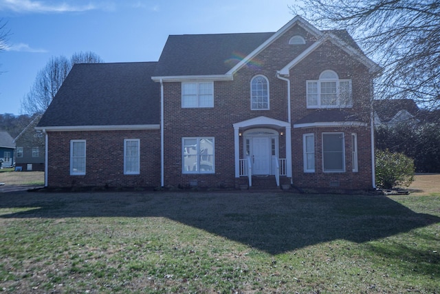 view of front facade with brick siding and a front lawn