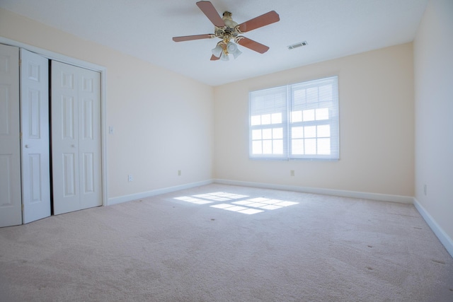 unfurnished bedroom featuring ceiling fan, visible vents, baseboards, a closet, and carpet