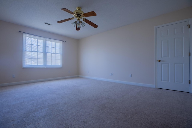 carpeted spare room with a ceiling fan, visible vents, and baseboards