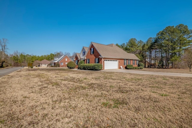 view of home's exterior featuring a garage, brick siding, a yard, and driveway