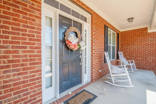 property entrance with a porch and brick siding