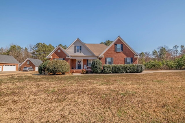 view of front of home with brick siding, a front lawn, a porch, and a detached garage