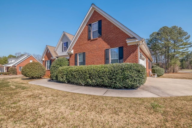 view of side of property featuring a garage, brick siding, a lawn, and driveway