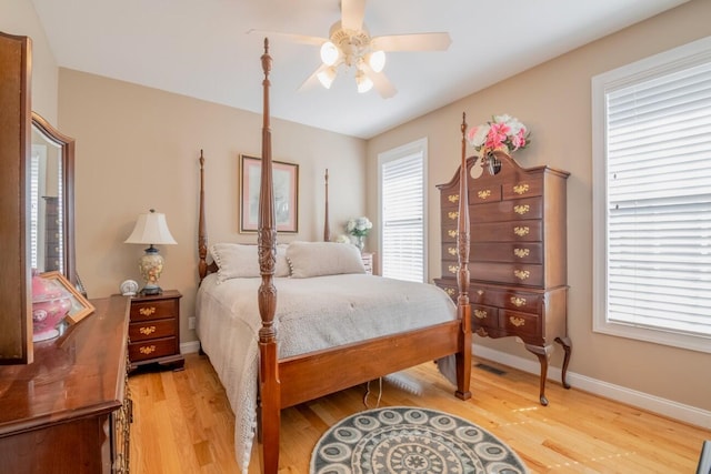 bedroom with light wood-style floors, visible vents, baseboards, and a ceiling fan