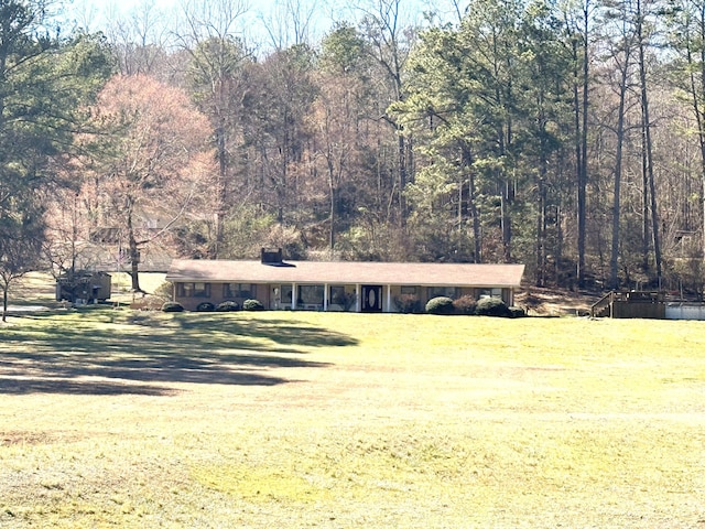 view of front of property featuring a wooded view and a front yard