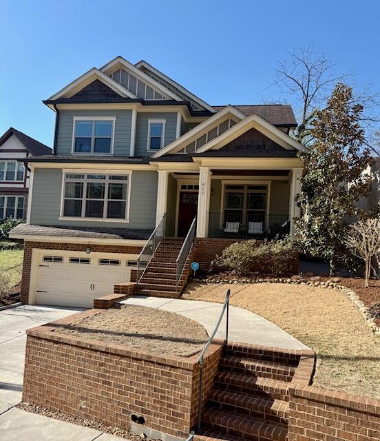 craftsman-style house with brick siding, stairway, a porch, concrete driveway, and an attached garage