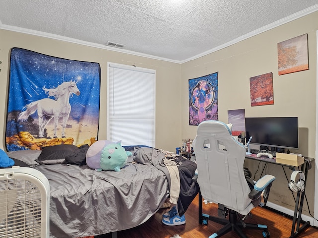 bedroom featuring crown molding, a textured ceiling, visible vents, and wood finished floors