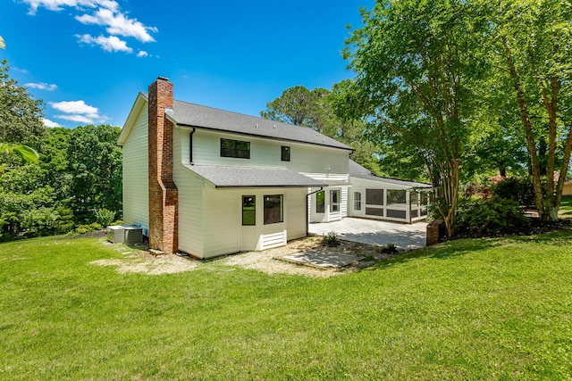 back of house with central air condition unit, a sunroom, a yard, a chimney, and a patio area