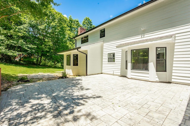 back of property featuring a patio area, a yard, and a chimney