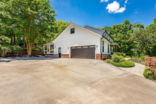 view of side of home with a garage, concrete driveway, brick siding, and board and batten siding