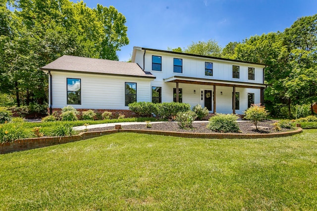 view of front of home with a front yard, covered porch, and brick siding