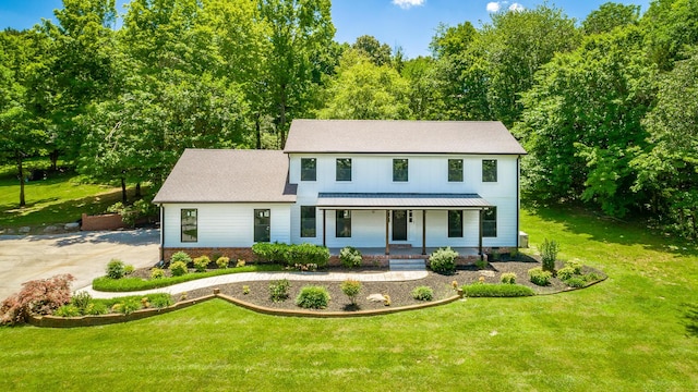 view of front of house with a porch, a front yard, a standing seam roof, metal roof, and driveway