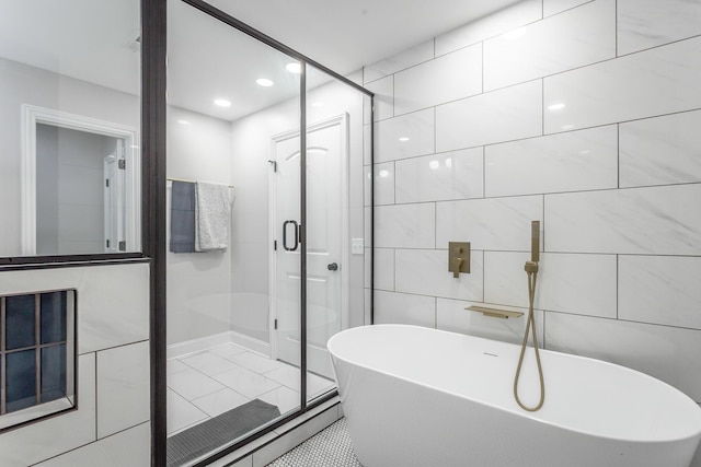 full bath featuring a freestanding tub, tile walls, a shower stall, and tile patterned floors