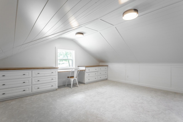 bonus room with lofted ceiling, built in study area, and light colored carpet