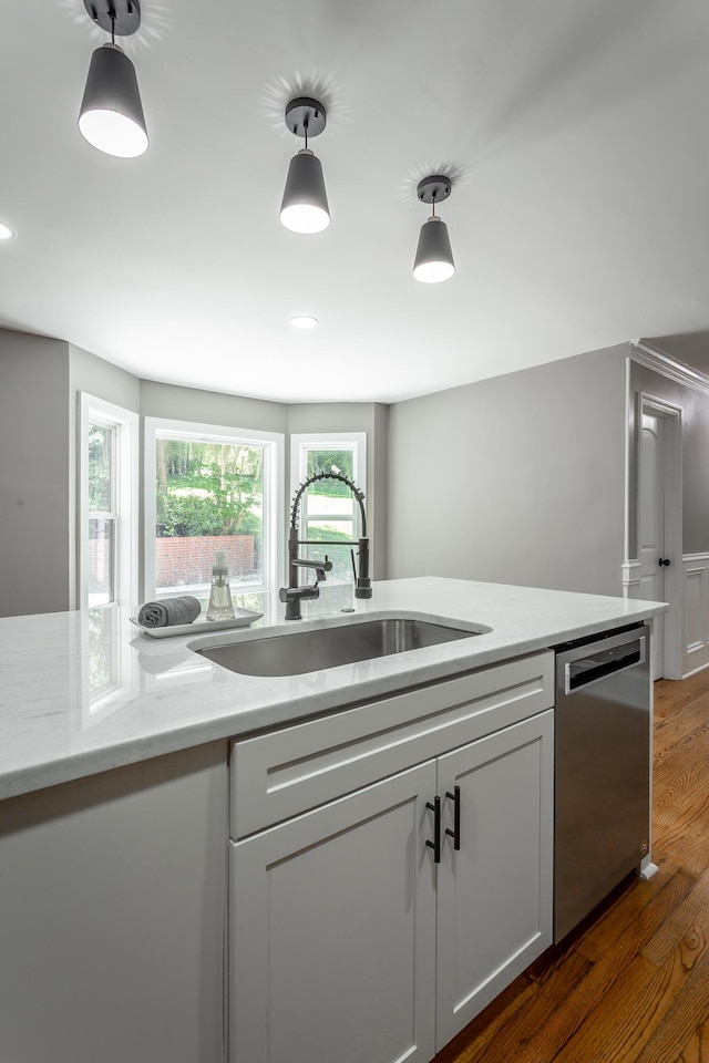 kitchen featuring dishwasher, hanging light fixtures, a sink, and wood finished floors