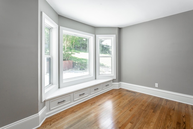 spare room featuring light wood-type flooring, visible vents, and baseboards