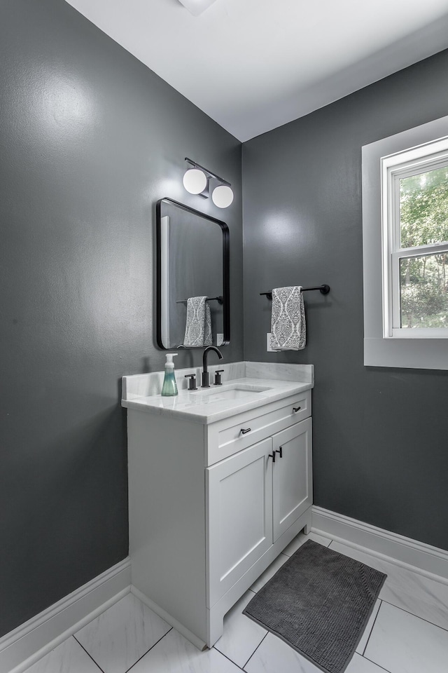 bathroom with marble finish floor, vanity, and baseboards