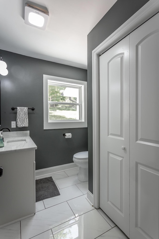 bathroom featuring baseboards, vanity, and toilet