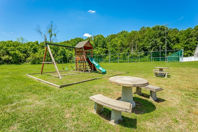 communal playground featuring a lawn and fence