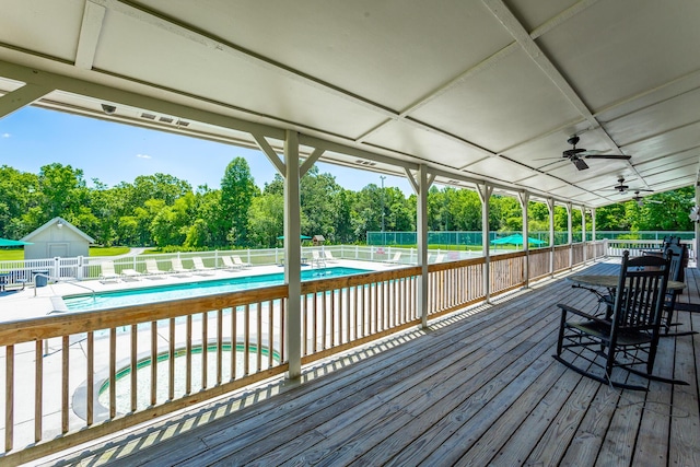 deck with a ceiling fan, fence, and a community pool