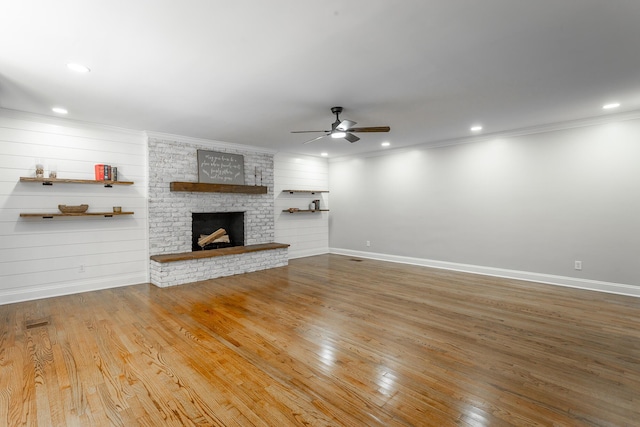 unfurnished living room with baseboards, ornamental molding, wood finished floors, a fireplace, and recessed lighting