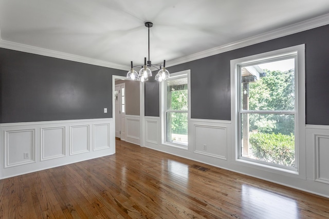 unfurnished dining area featuring ornamental molding, dark wood-style flooring, visible vents, and a wainscoted wall