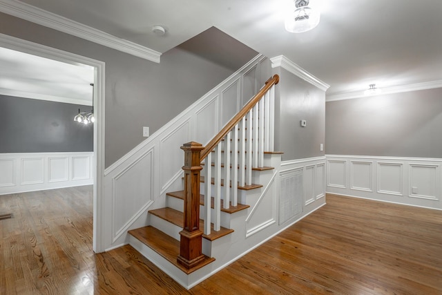 stairway featuring visible vents, ornamental molding, wood finished floors, and wainscoting