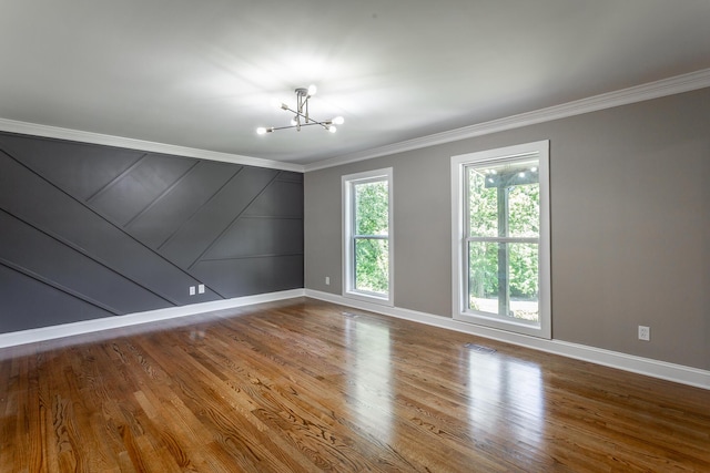 empty room featuring an inviting chandelier, visible vents, ornamental molding, and wood finished floors