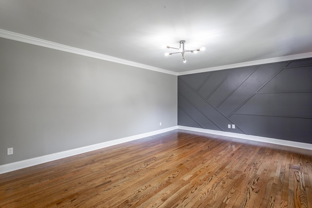 unfurnished room with an inviting chandelier, crown molding, baseboards, and wood finished floors