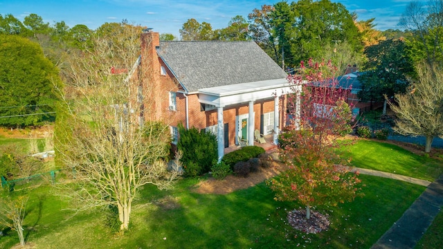 view of front of property with a front lawn, a chimney, and brick siding