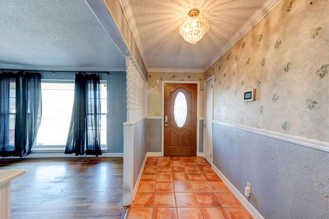 foyer entrance with crown molding, a textured wall, an inviting chandelier, a textured ceiling, and baseboards