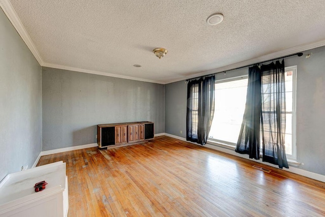 unfurnished room featuring light wood-style floors, crown molding, visible vents, and a wealth of natural light