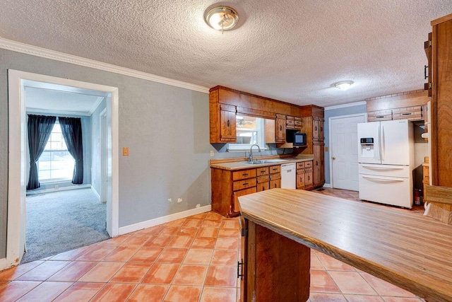 kitchen with white appliances, brown cabinets, crown molding, and light tile patterned floors