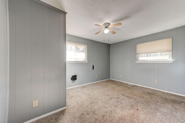 unfurnished room with carpet floors, visible vents, a ceiling fan, a textured ceiling, and baseboards