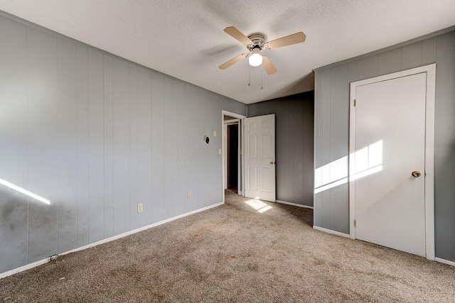 unfurnished bedroom featuring carpet flooring, ceiling fan, a textured ceiling, and baseboards