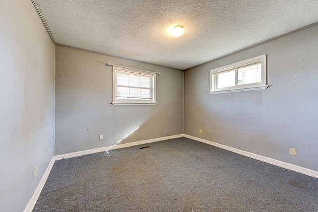 carpeted empty room with a textured ceiling, visible vents, and a wealth of natural light