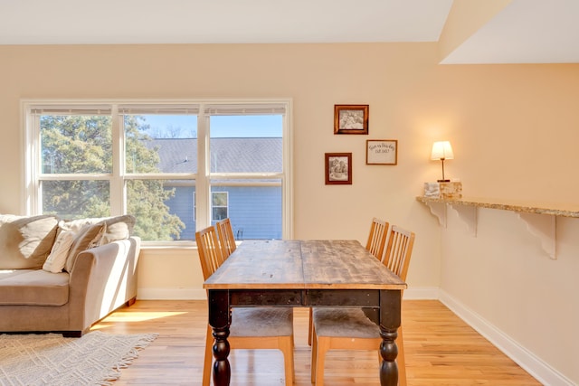 dining space with light wood-type flooring, baseboards, and a wealth of natural light