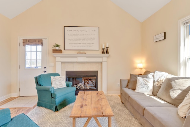 living room featuring lofted ceiling, wood finished floors, a tile fireplace, and baseboards