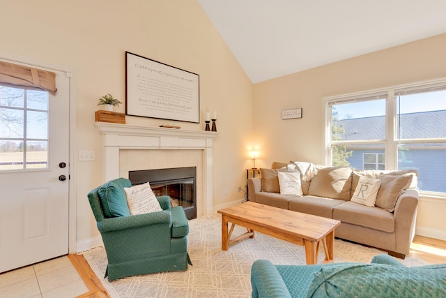 living area with lofted ceiling, tile patterned flooring, a tile fireplace, and baseboards