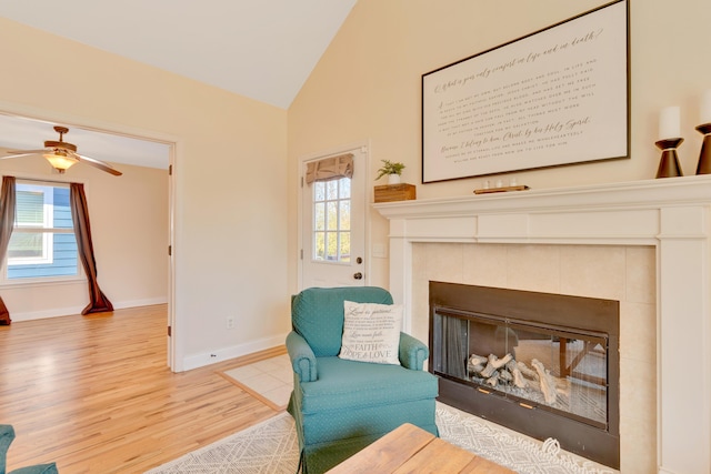 living area with plenty of natural light, a fireplace, vaulted ceiling, and wood finished floors