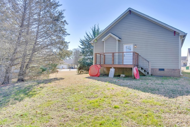 rear view of property featuring crawl space, a wooden deck, and a yard