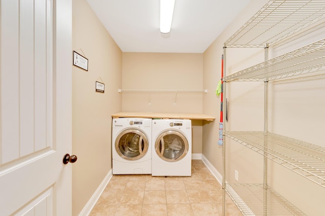 laundry area with laundry area, light tile patterned flooring, washer and clothes dryer, and baseboards