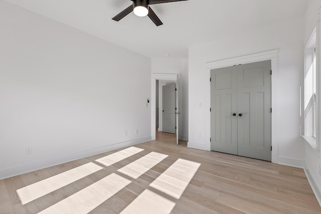 unfurnished bedroom with baseboards, a closet, a ceiling fan, and light wood-style floors