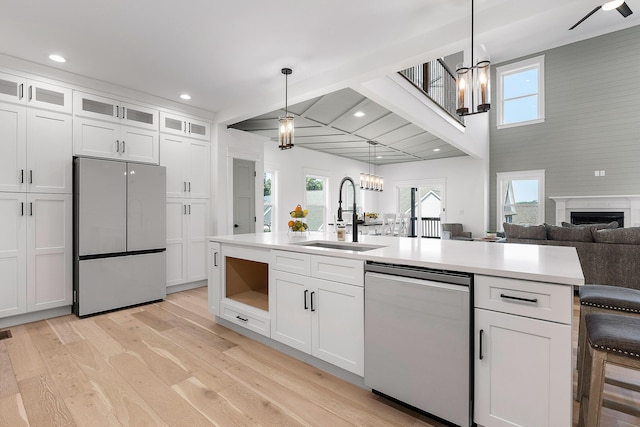 kitchen with a chandelier, stainless steel appliances, a sink, light wood finished floors, and plenty of natural light